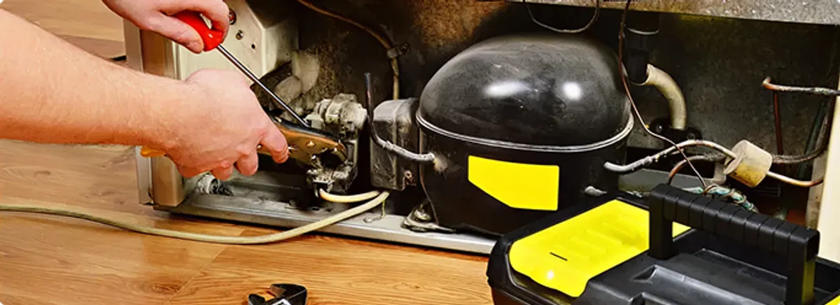 Refrigerator repair technician fixing the compressor and wiring in Greenwell Springs, LA