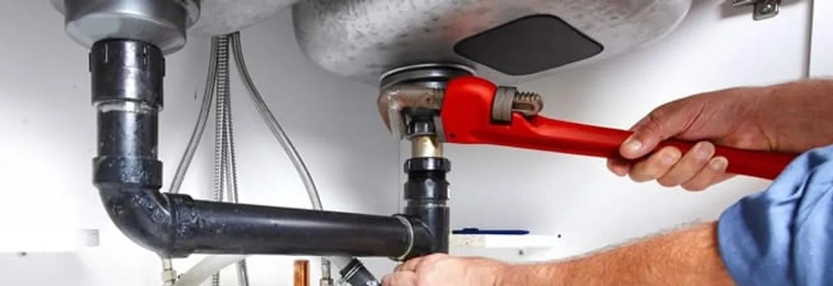 Garbage disposal repair technician tightening the sink drain and disposal connection in Baton Rouge, LA
