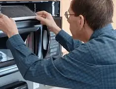 Appliance repair technician replacing a microwave vent filter in Baton Rouge, LA