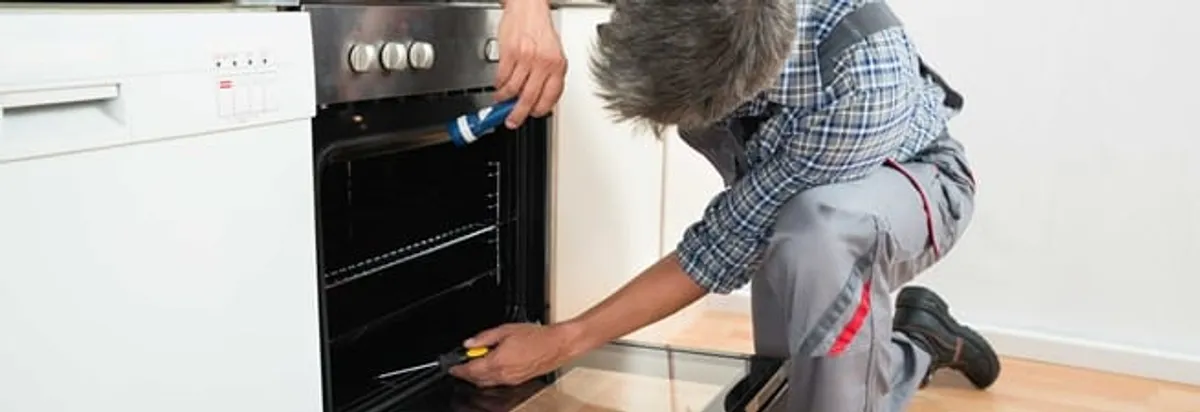 Oven repair technician inspecting and servicing an electric oven in Baton Rouge, LA