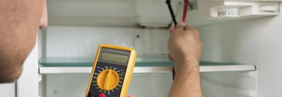 Refrigerator repair technician testing electrical components with a multimeter in Baton Rouge, LA